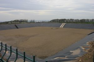 Earth banked and sheet lined slurry lagoon part filled with slurry