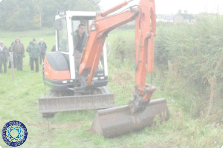An orange digger working in a drain alongside a field hedge.