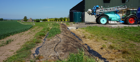 A biobed with a tractor and sprayer parked nearby.