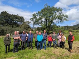Picture of NetZero Arran Farm advisory group standing in field in front of trees. River in background but hidden by shrubs