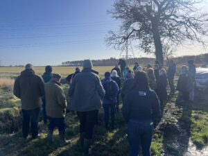 Group of farmers standing on grass field looking at ditch, discussing with SEPA what they can and can't do with regard to ditch management